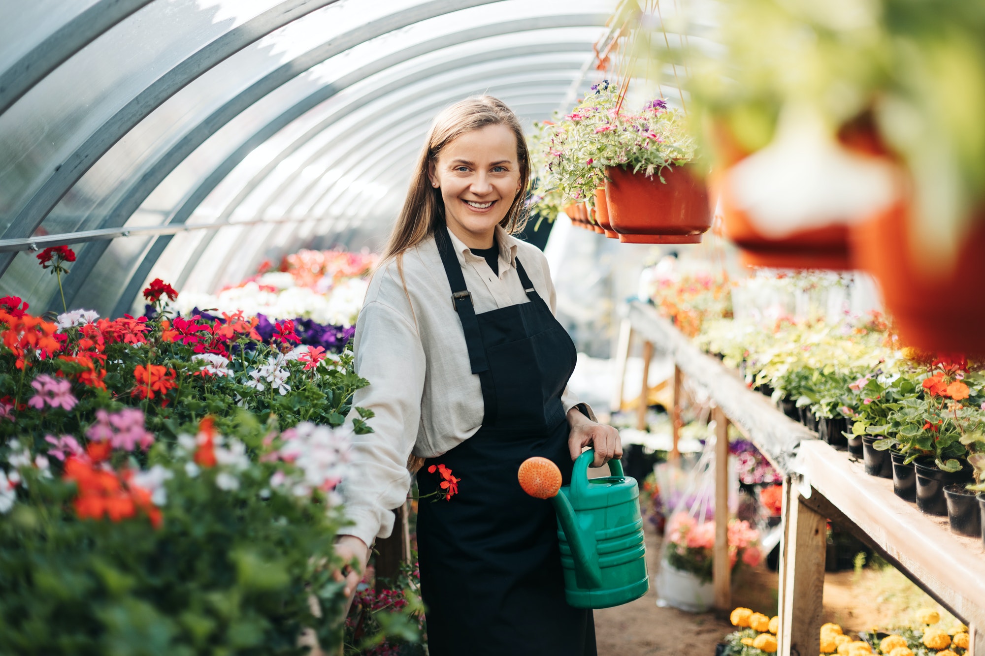 portrait-of-a-young-gardener-woman-watering-flowers-in-a-greenhouse-daily-care-of-plants.jpg