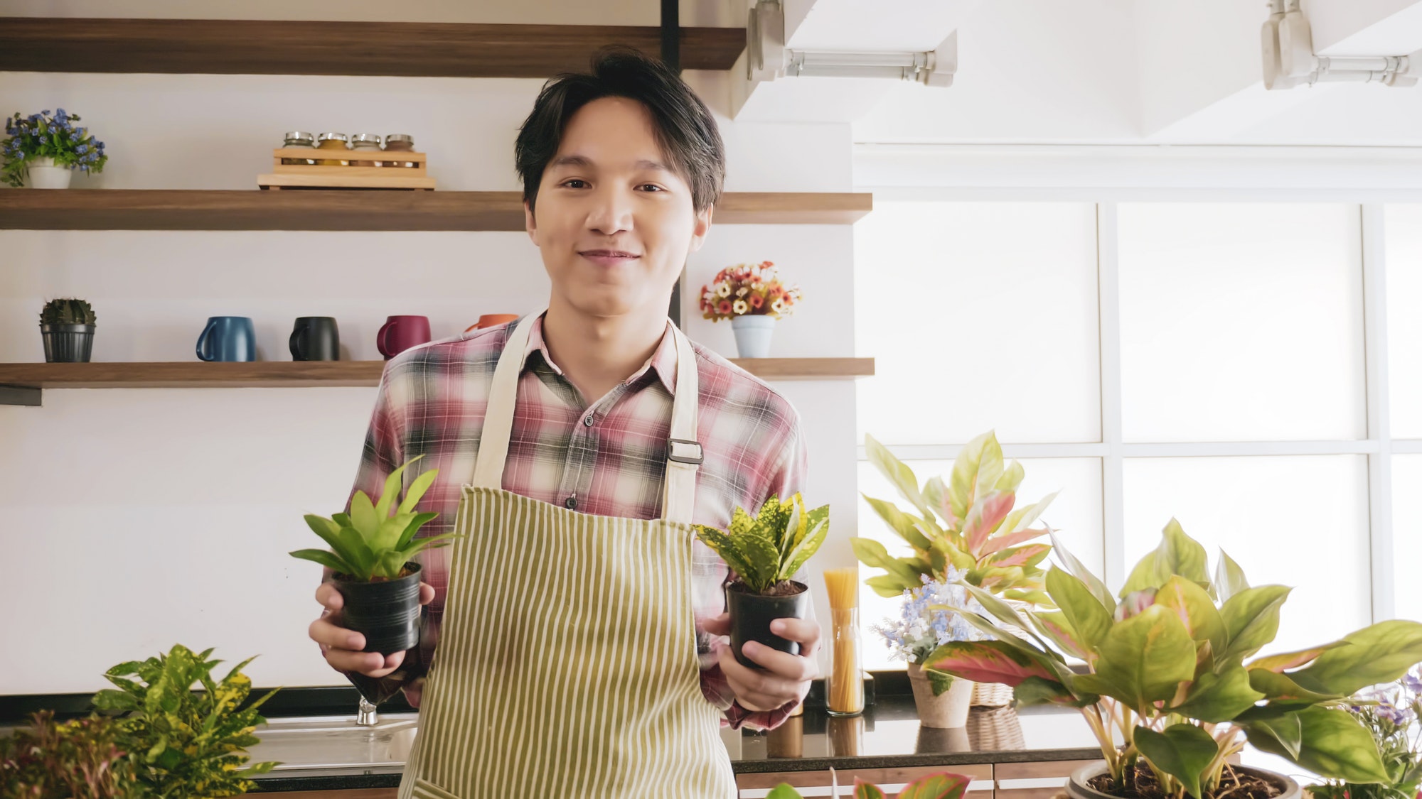 young-gardener-man-holding-flowerpot-in-the-room-.jpg